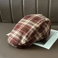 Dettaglio in primo piano di un cappello piatto a quadri marroni su sfondo di pelle. - Caffè