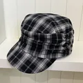 Close-up of a retro black and white plaid newsboy cap with elegant pleated side details. - Black Plaid