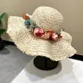Hand-woven wide brim straw hat with floral decoration for beach vacation. - Off White