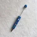 Detailed macro view of a handmade ballpoint pen covered in blue rhinestones and colorful stones - Deep Blue with AB Rhinestones