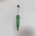 Macro detail of a handmade green rhinestone beaded pen on soft grey textured felt - Light Green with AB Rhinestone Heart