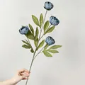 Handgehaltene Detailansicht einer realistischen blauen künstlichen Pfingstrose mit Blüten - Hellblau