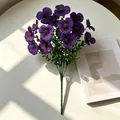 Nahaufnahme violetter Stiefmütterchen-Kunstblumen mit Eukalyptusstielen im natürlichen Sonnenlicht. - Lila