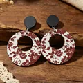 Primer plano de pendientes vintage de madera con estampado floral rojo sobre fondo blanco - Floral