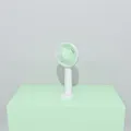 Portable handheld USB fan in mint green and white standing on a matching green base - Green