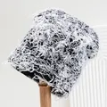 Distressed camouflage knitted beanie with black and white fringe detail on wooden stand - M (56-58cm) / White