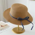 Handmade raffia straw sun hat featuring a blue denim bow accent on a gold display stand - Khaki