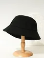 Black canvas bucket hat with detailed stitching shown on a minimalist wooden stand - M (56-58cm) / Black
