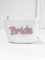Close-up of white woven bride pouch with pink pearl and rhinestone lettering. - Pink Pearl Style