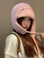 Vista dettagliata di un cappello di maglia rosa con paraorecchie e lacci per l'inverno - Rosa