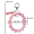 Pink silicone bead wristlet keychain featuring soft tassel, daisy, and butterfly charms. - Silicone Bead Wristlet Keychain / Pink