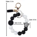 Black and white silicone bead wristlet keychain with butterfly and daisy charms. - Silicone Bead Wristlet Keychain / Black
