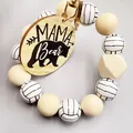 Detalle de una placa de madera grabada Mama Bear en un llavero de cuentas de voleibol - Estilo Voleibol
