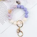 Purple and white silicone beaded wristlet keychain with floral prints and gold clasp. - Purple