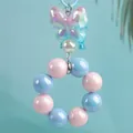 Precioso llavero de cuentas color caramelo con mariposa iridiscente y detalle de perla - Azul claro