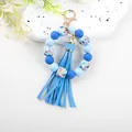 Close-up of blue silicone bead bracelet with floral octagon beads and tassel detail. - Print Blue