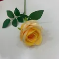 Nahaufnahme einer einzelnen gelben künstlichen Rose mit realistischen grünen Blättern - Gelb