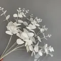Close-up detail of white artificial eucalyptus bundle held against a minimalist grey wall - 16 Branches Eucalyptus (YD202230) / Silk Screen White