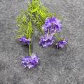 Detaillierte Draufsicht auf eine künstliche Kornblume mit fünf violetten Blüten auf Grau - Dunkellila