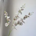 Detailed close-up of white artificial Oncidium orchid petals with realistic brown spots - White