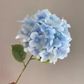Detailed close-up of a realistic light blue artificial hydrangea flower on a green stem. - Sky Blue