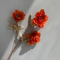 Detailed view of a three-headed orange artificial peony on a neutral gray background. - Dark Orange