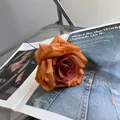 Einzelner künstlicher orangefarbener Rosenblütenkopf auf Magazin für die Heimdekoration - Orange-Kaffee