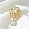 Detailed macro view of a vintage palace-style gold brooch with crystals on white silk. - Gold