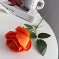 Detailopname van een levendige oranje kunstmatige roos met zijden bladeren - Oranje