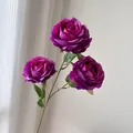 Vista detallada de tres rosas de seda artificiales de color púrpura oscuro con hojas. - Violeta Oscuro
