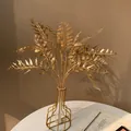 Gros plan d'élégantes feuilles de fougère artificielles dorées dans un vase moderne. - Feuille d'Eucalyptus Dorée (Style 26)