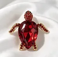 Gros plan détaillé d'une broche tortue dorée ornée de cristaux rouges facettés. - Rouge
