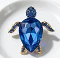 Gros plan sur la carapace en cristal bleu facetté et les détails en strass de la broche tortue - Bleu Saphir