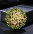 Close-up of vintage luxury crystal flower brooch with green and yellow rhinestones. - White+Green