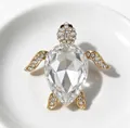 Close-up of elegant turtle brooch with sparkling clear crystals and gold-tone finish - White