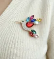 Colorful hummingbird brooch with sparkling crystals pinned on a white knit sweater detail - Colorful