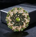 Detailed view of a vintage luxury brooch with green rhinestones in a floral wreath design. - Green And White