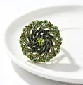 Detailed macro shot of vintage gold flower brooch with sparkling green rhinestones - Green