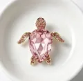 Close-up of elegant pink crystal turtle brooch with gold plating and fine diamond accents - Pink