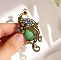 Detailed view of a vintage peacock brooch featuring colorful rhinestones held in hand - Vintage Peacock Style