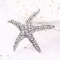 Gedetailleerde close-up van een vintage zilveren zeester broche met strass steentjes - Zilver + Witte Strass