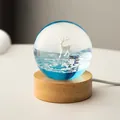 Decorative resin crystal ball night light featuring white deer and natural wood base - Glacier Elk (Plug-in)