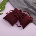 Primer plano de elegantes bolsitas de terciopelo granate para joyas con cordón - Borde ondulado / 7*9cm / Burdeos
