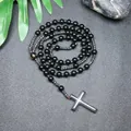 Detalle de un rosario de cuentas negras con colgante de cruz sobre fondo de piedra. - Vidrio Negro