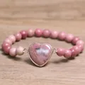 Detail van een 8mm roze natuursteen kralenarmband met een hartvormige stenen bedel. - Rode Houtnerf