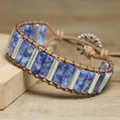 Detail shot of blue stone and leather wrap bracelet with silver tubes on wood surface - Blue Spot Jasper