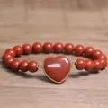 Close-up of red natural stone beaded bracelet with heart-shaped stone centerpiece - Red Jasper
