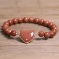 Detailed view of 8mm goldstone beaded bracelet featuring a sparkling heart-shaped pendant. - Gold Sandstone