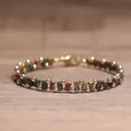 Handgemaakte boheemse Tila-kralenarmband met gouden accenten op een houten achtergrond - Picasso steen