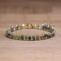 Handgemaakte TILA-kralen geweven armband met groene en gouden aardetinten op hout - Indische Agaat